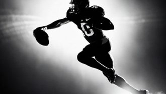 Black and white silhouette of a football player running with the ball.