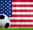 Soccer ball on grass with the American flag in the background