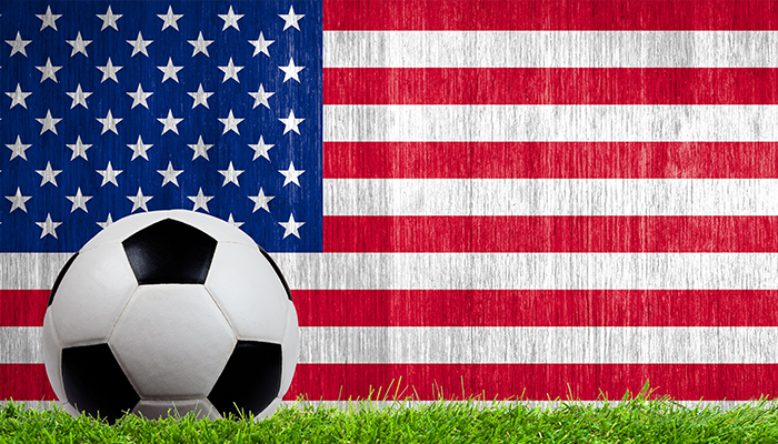 Soccer ball on grass with the American flag in the background