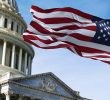 The American flag waving against the US Capitol