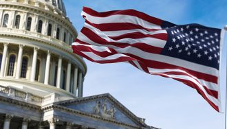 The American flag waving against the US Capitol