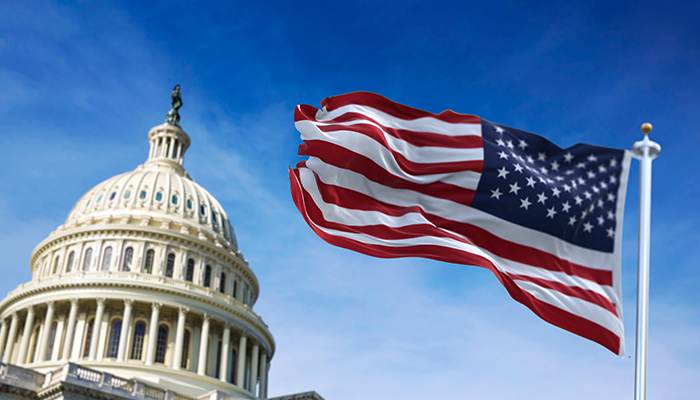 American flag waving next to US Capitol Hill Building