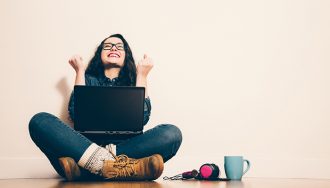 Happy woman sitting on the floor with a laptop