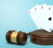 Playing cards on round wooden block and brown wooden gavel