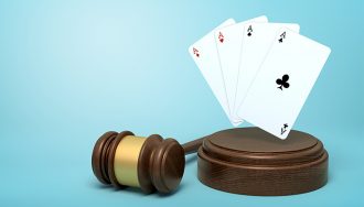 Playing cards on round wooden block and brown wooden gavel